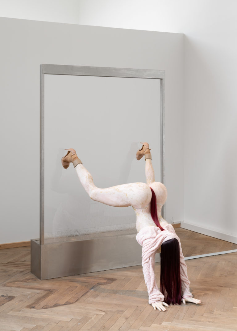 skulptur af kvinde der twerker på hovedet med benene i luften mens hun bløder fra underlivet