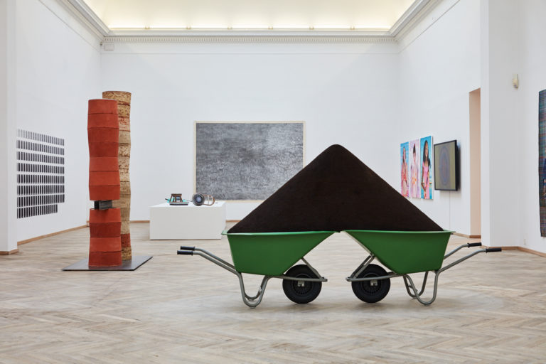 skulptur: to trillebører der sidder sammen, læsset med jord.