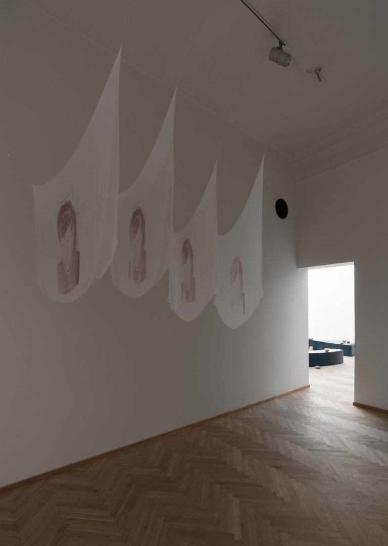 Fire stykker tyndt stof med tryk hænger i loftet på række.