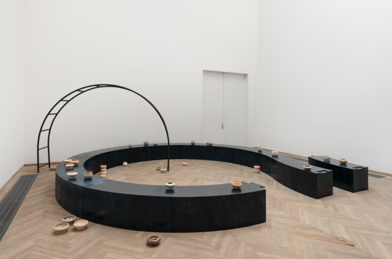 Stor ovalformet skulpturinstallation i sort.