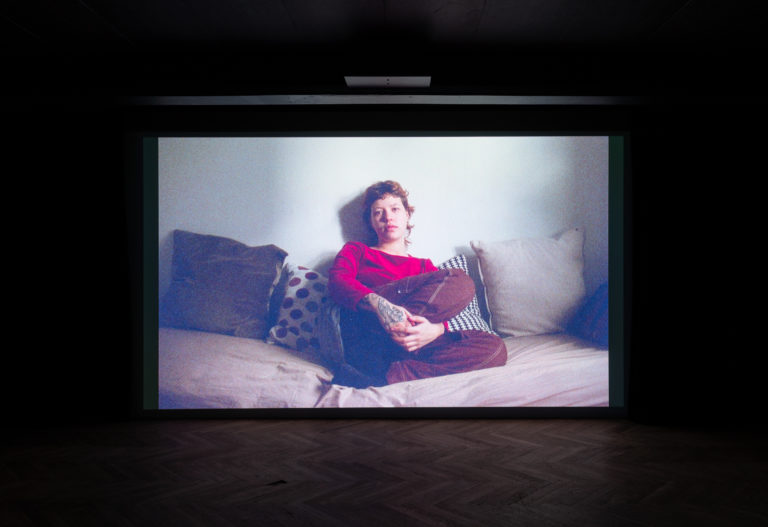 Still fra film af kvinde der sidder i sin seng