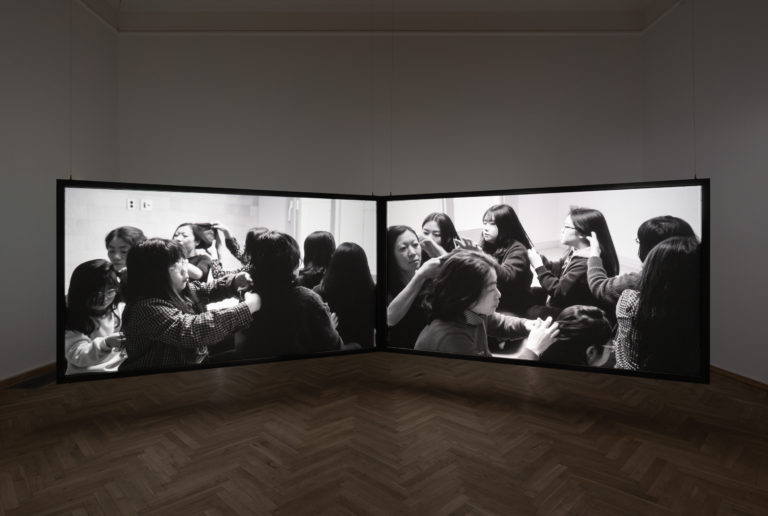 to store videoskærme der viser kvinder der fletter hinandens hår