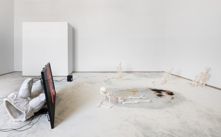 Videoinstallation: Skeletter kigger på videoskærmen, blod og kaffepletter på gulvet.