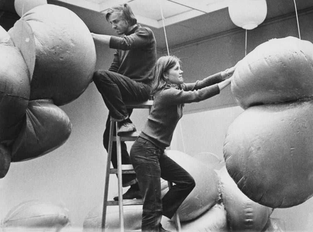Two people are installing a sculpture in an exhibition space.