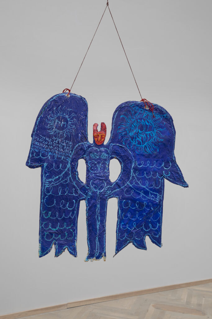 A blue figure with wings, hanging from the ceiling by a red string.