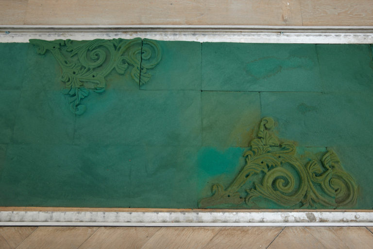 Ornamenter i grønne nuancer, placeret som en del af trægulvet.
