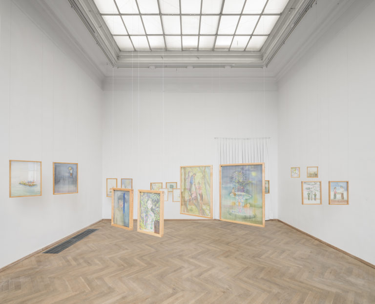 A bright exhibition room with many wooden frames hanging freely from the ceiling. Each frame contains a watercolor motif painted on stretched silk.