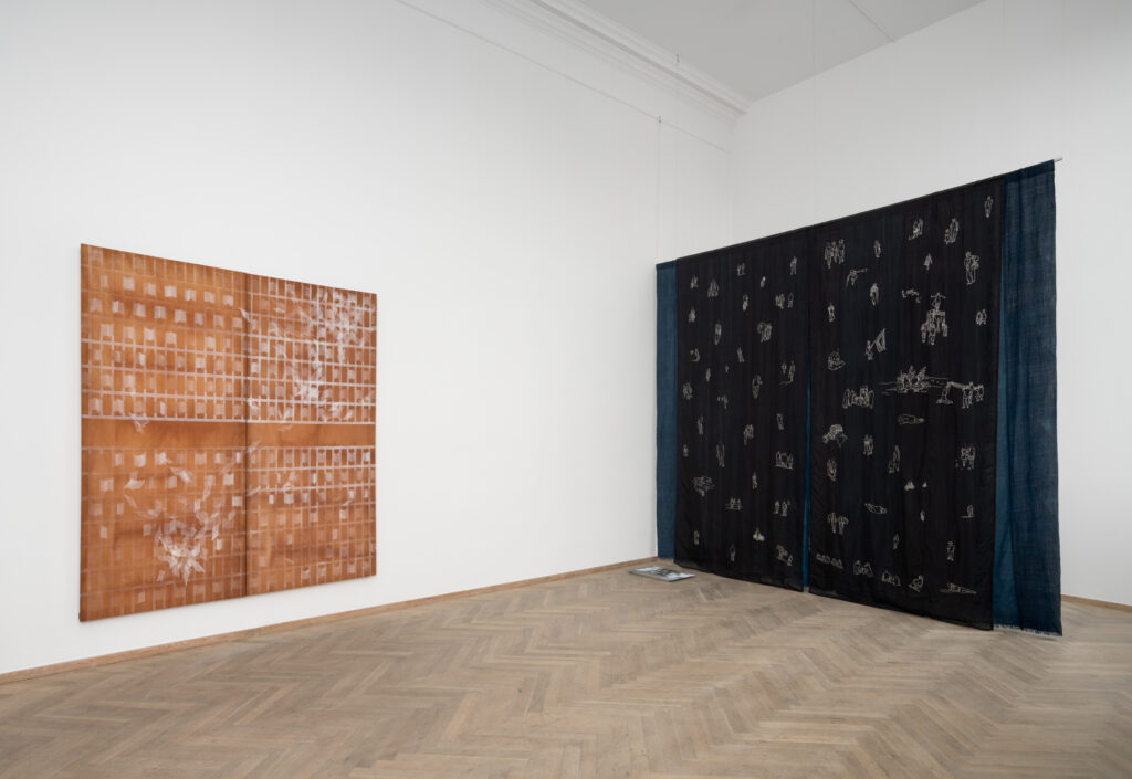 Ophængt stof med illustrationer i et udstillingsrum.