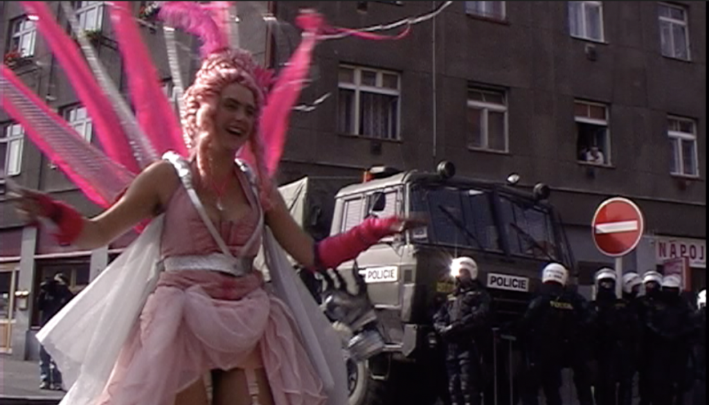 En kvinde klædt i lyserød, med politiet i baggrunden.