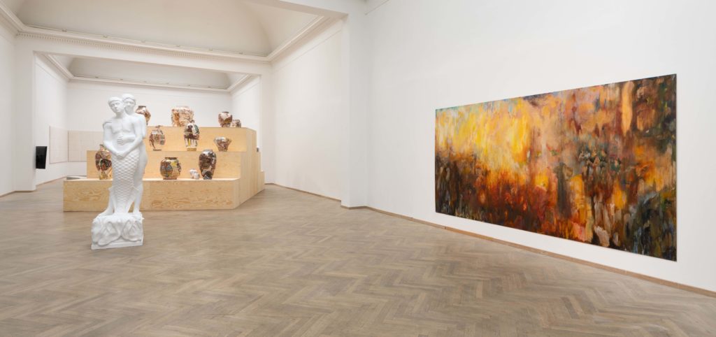 I et udstillingsrum, står en skulptur af to personer, der omfavner hinanden.