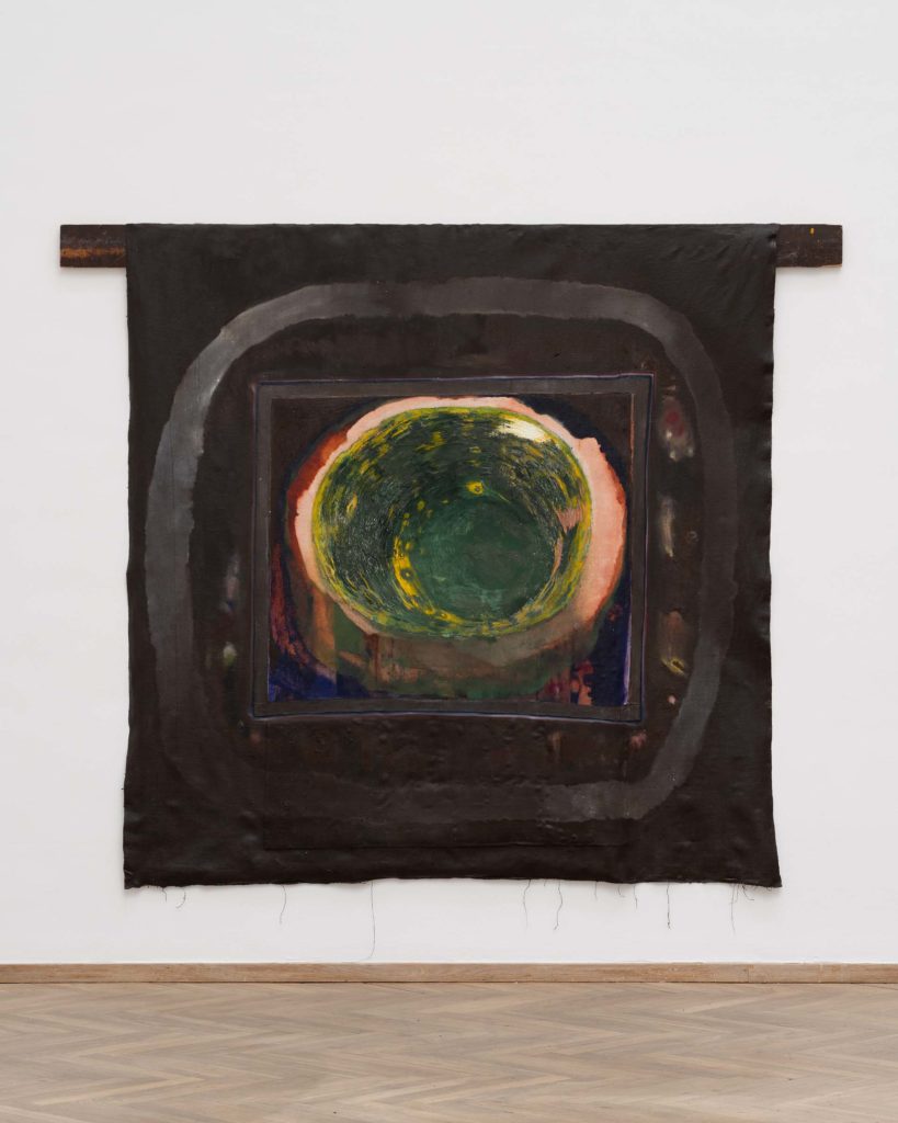 A painting on a black piece of fabric, hanging on the wall in an exhibition room.