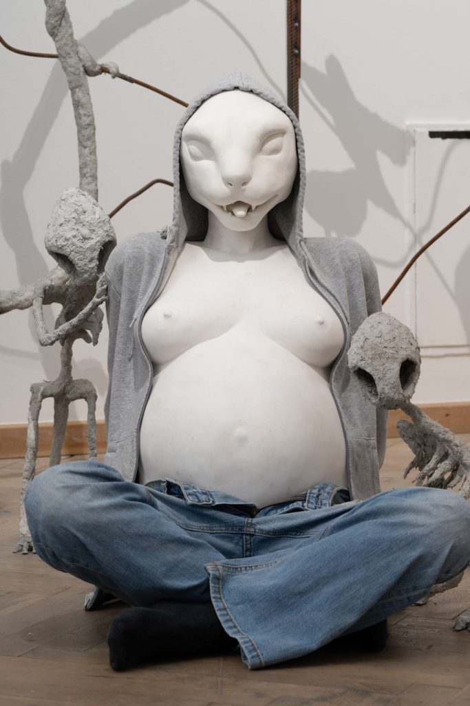 A sculpture of a pregnant woman with an animal face.