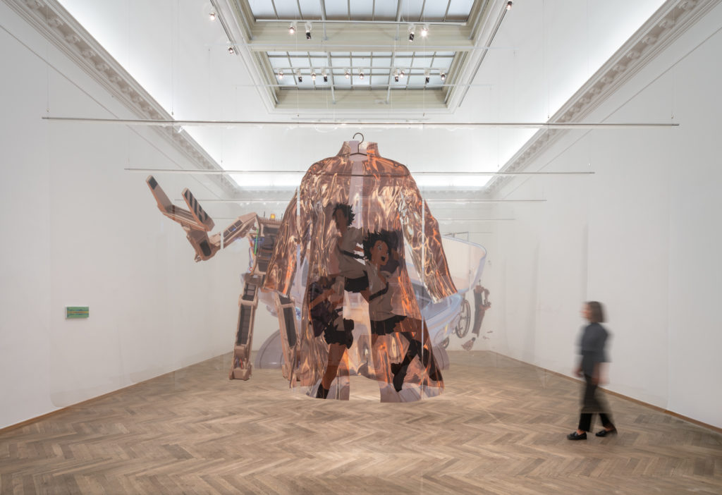 Et lyst udstillingsrum med et kunstværk, der hænger fra loftet.