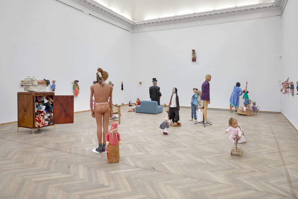 An exhibition space with a collection of dolls in different sizes.