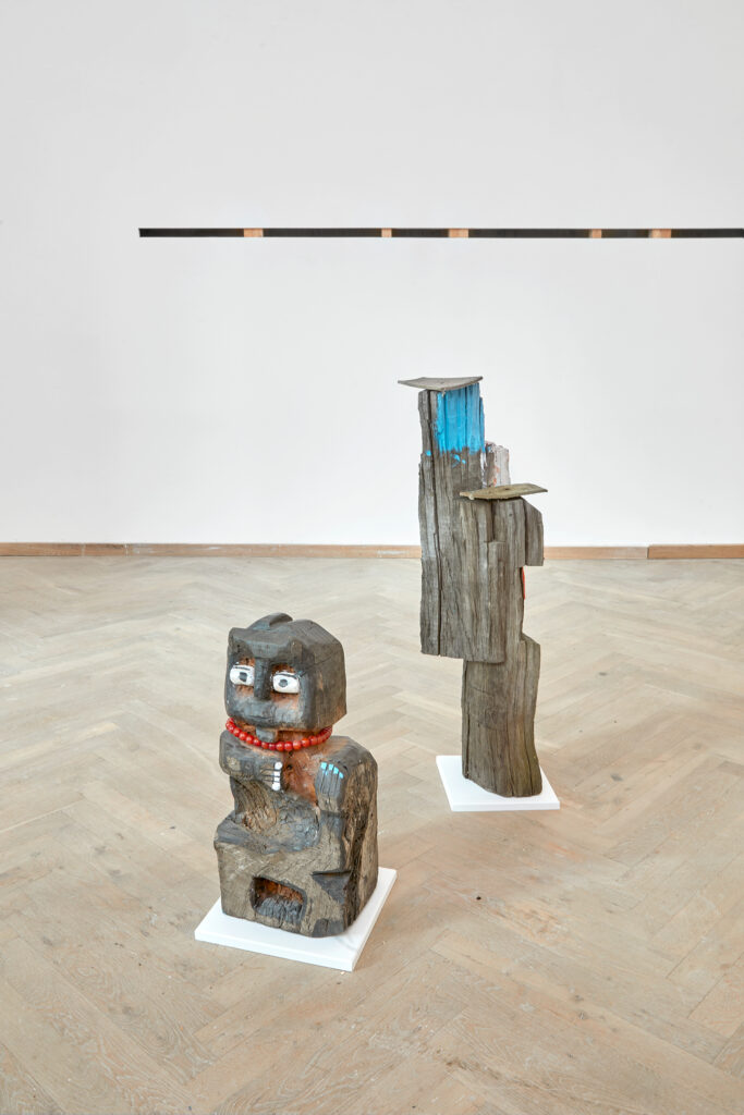 Two wooden sculptures in an exhibition room.