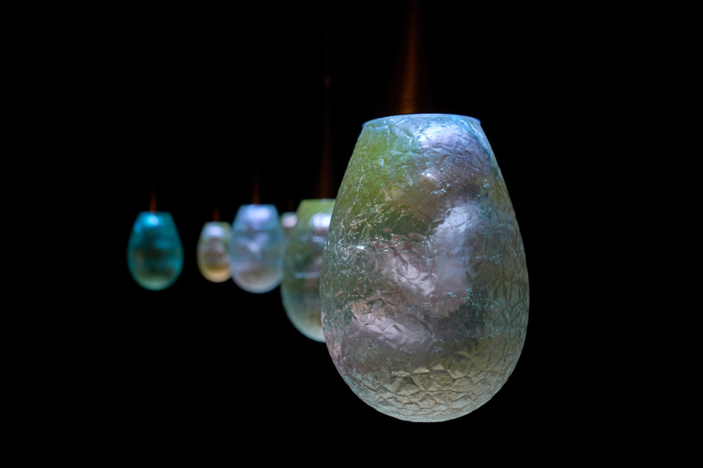 Containers hanging from the ceiling in an exhibition space.