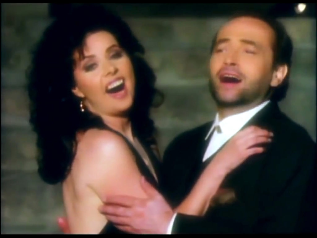 Man and woman in formal cloting singing with arms around each other